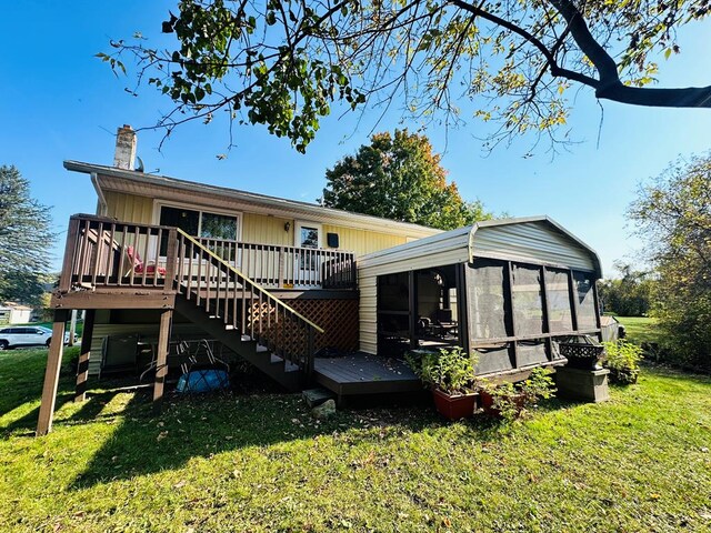 rear view of property with a lawn, a sunroom, and a deck