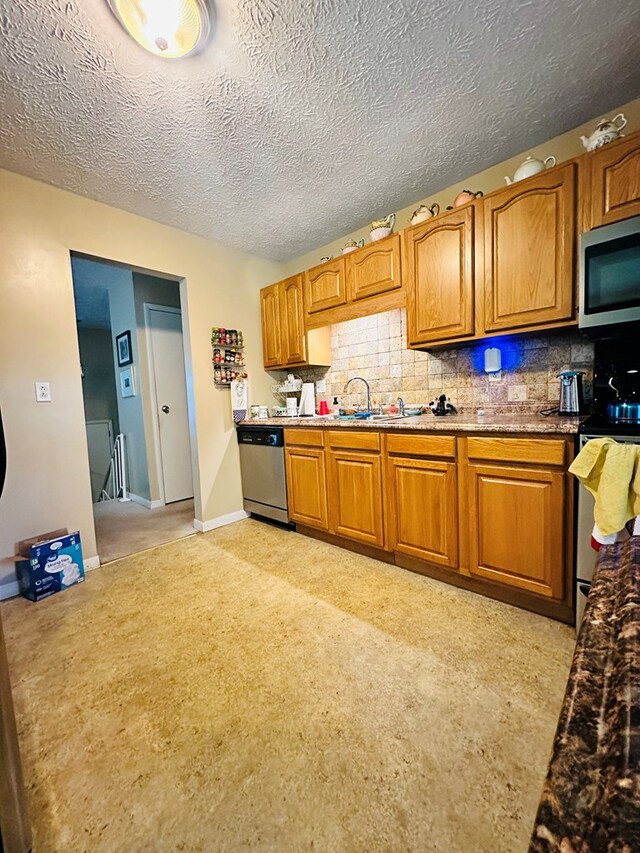 kitchen featuring sink, stainless steel appliances, light colored carpet, a textured ceiling, and decorative backsplash