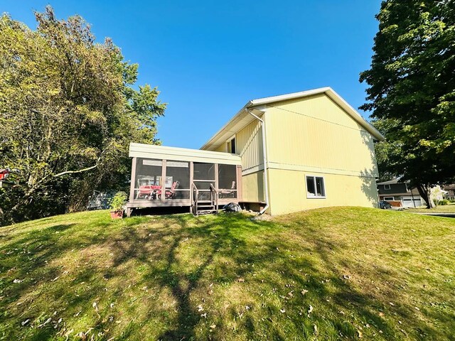 view of side of home with a sunroom, a wooden deck, and a lawn