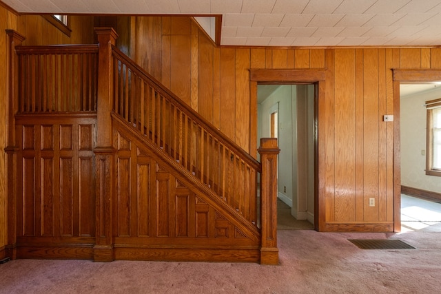 stairs featuring carpet and wood walls