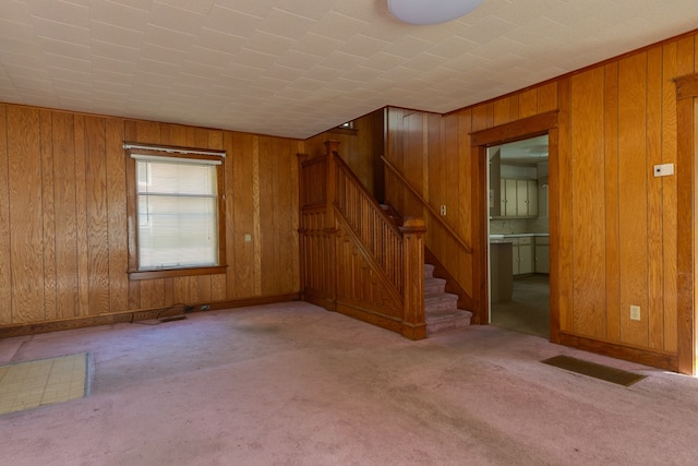 unfurnished living room with wooden walls and light colored carpet