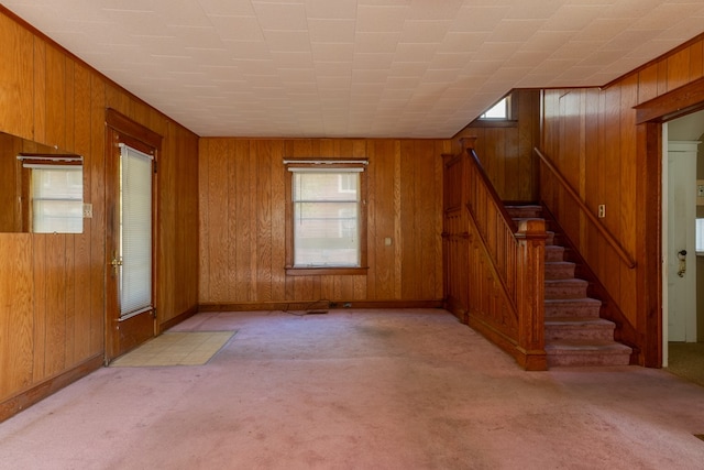 unfurnished living room with wood walls and light colored carpet