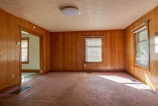 carpeted empty room with wood walls