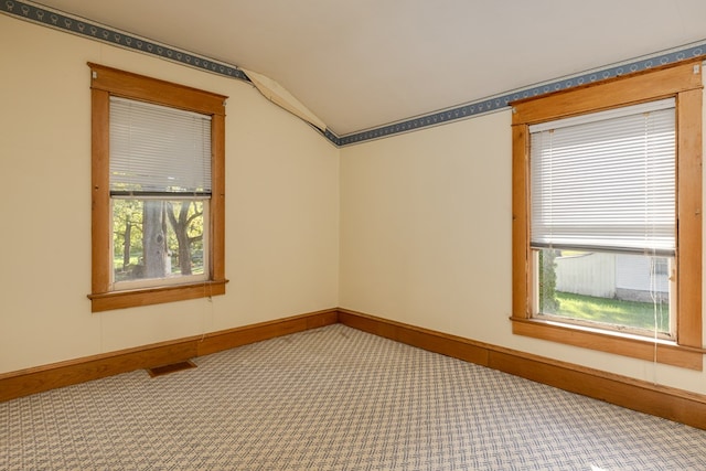 unfurnished room with carpet floors, vaulted ceiling, and plenty of natural light