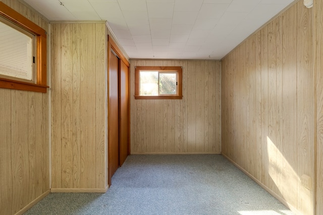 unfurnished room with wooden walls and light carpet