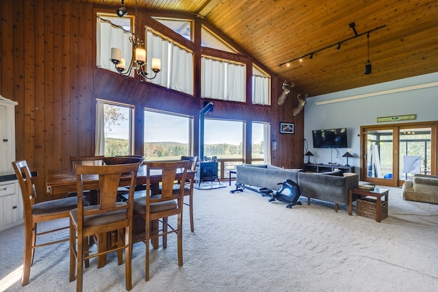 carpeted dining room featuring plenty of natural light, wooden ceiling, high vaulted ceiling, and a chandelier