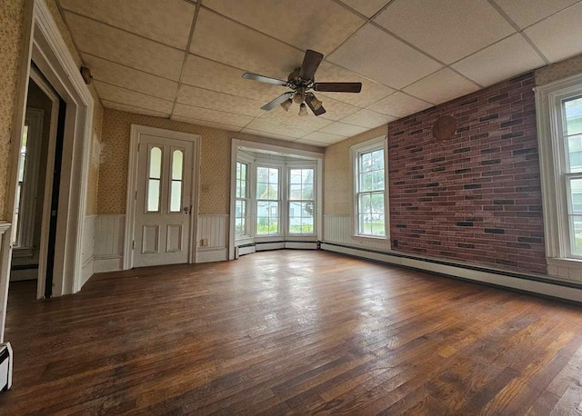 unfurnished room with a baseboard heating unit, dark hardwood / wood-style flooring, ceiling fan, and a paneled ceiling