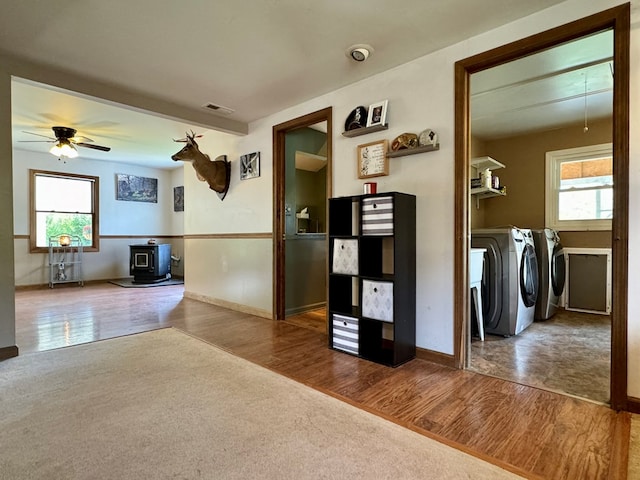 interior space featuring independent washer and dryer, hardwood / wood-style flooring, a wood stove, and a wealth of natural light