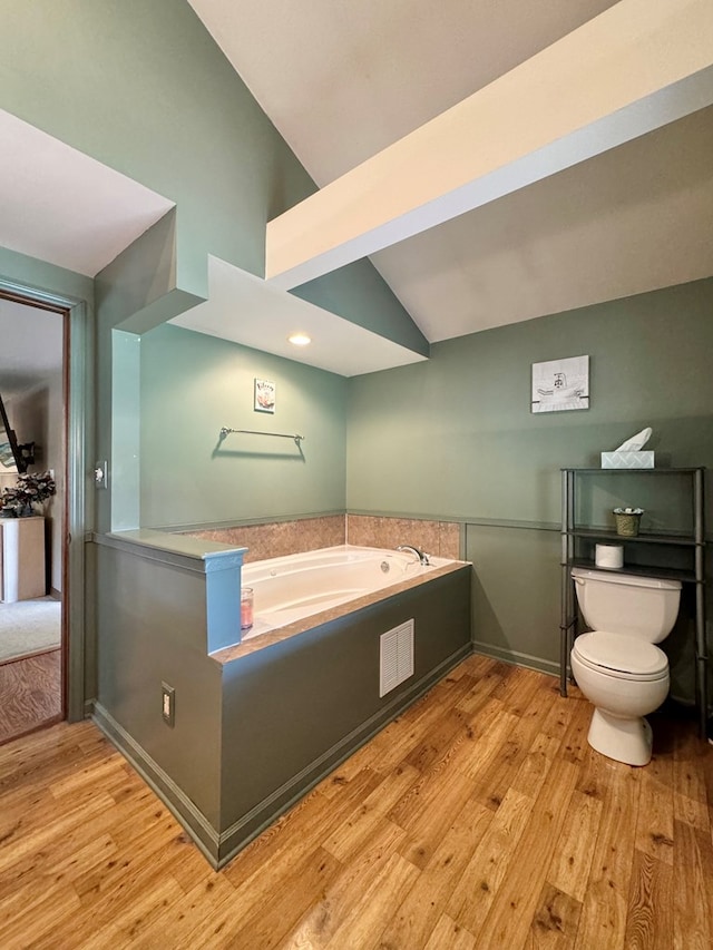 bathroom featuring a tub, toilet, lofted ceiling, and hardwood / wood-style flooring