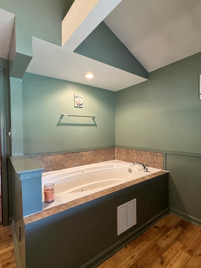 bathroom with a bathtub, lofted ceiling, and hardwood / wood-style flooring