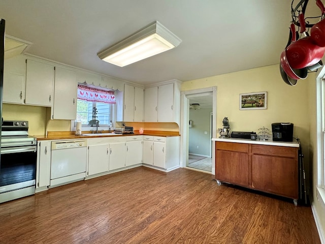 kitchen featuring white cabinetry, stainless steel stove, white dishwasher, and hardwood / wood-style flooring