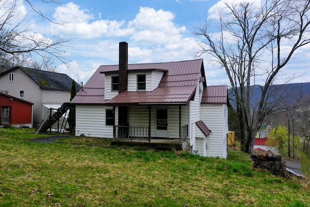 rear view of property featuring a yard and covered porch