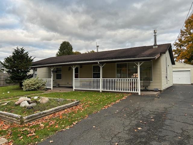 view of front facade featuring an outbuilding, a garage, a front lawn, and a porch