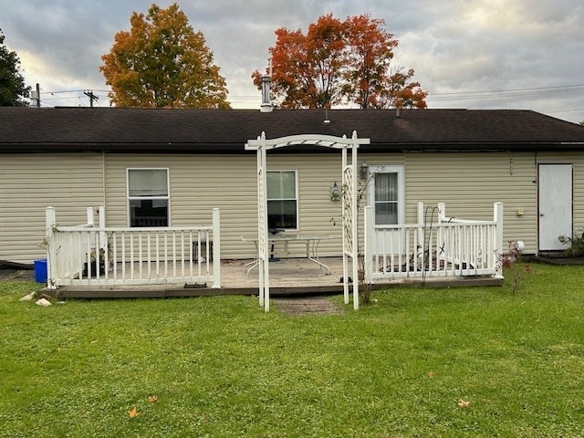 rear view of house featuring a wooden deck and a lawn