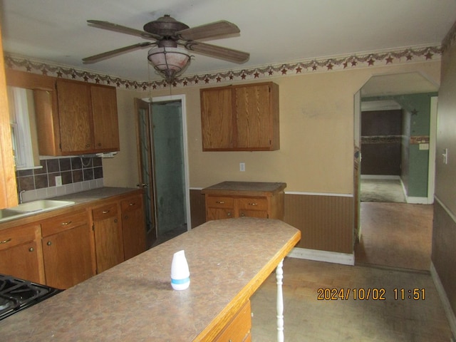 kitchen with stovetop, decorative backsplash, ceiling fan, and sink