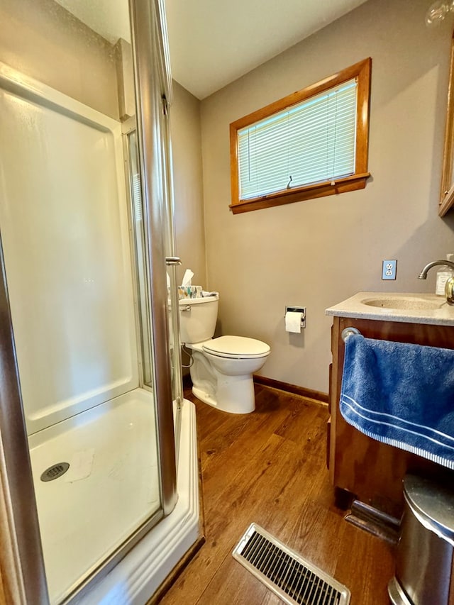 bathroom with vanity, toilet, a shower with shower door, and wood-type flooring