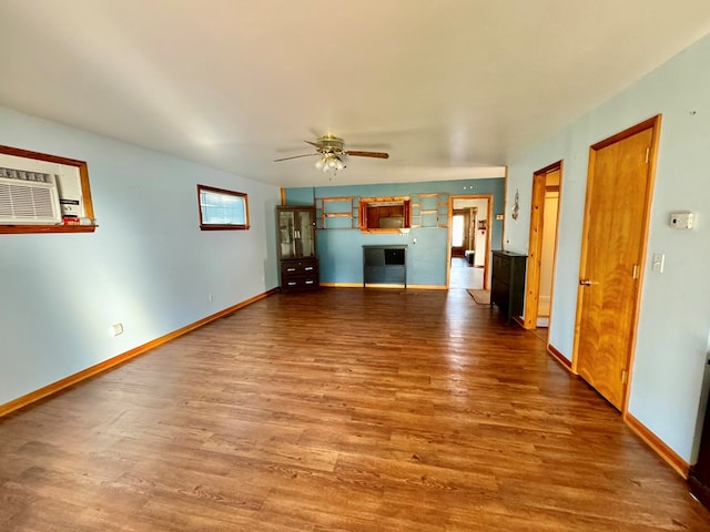 unfurnished living room with wood-type flooring, an AC wall unit, and ceiling fan