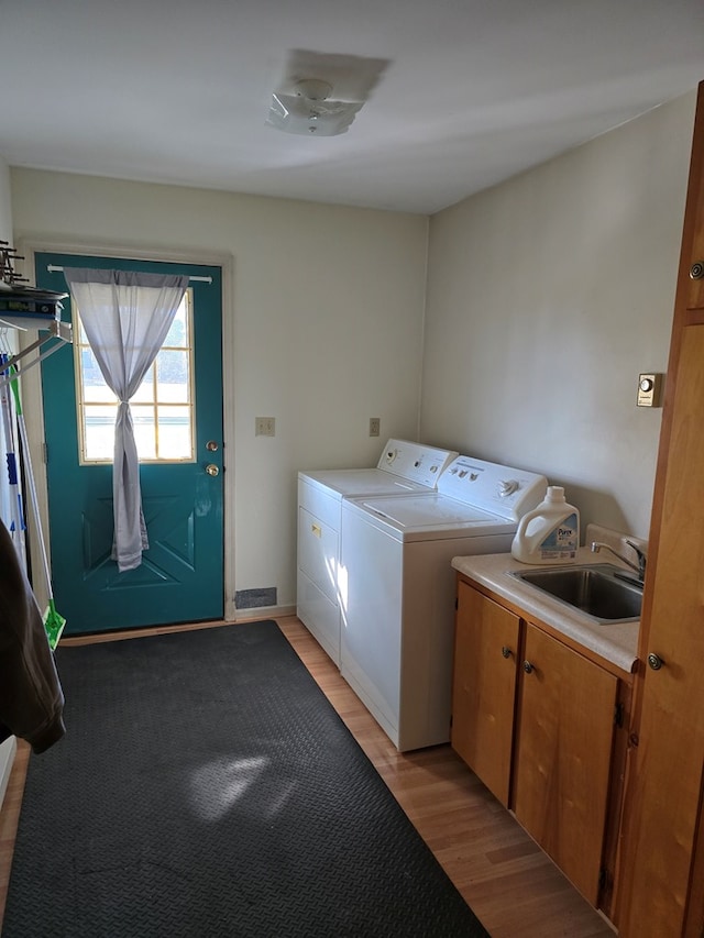 laundry area with washer and dryer, sink, cabinets, and light hardwood / wood-style flooring