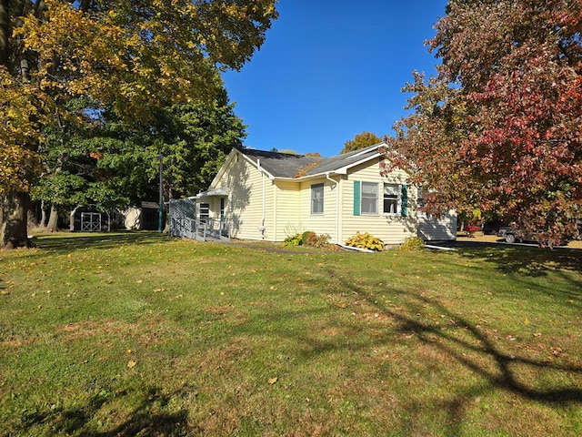 view of side of home with a yard and a storage shed