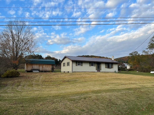 single story home featuring an outbuilding and a front yard