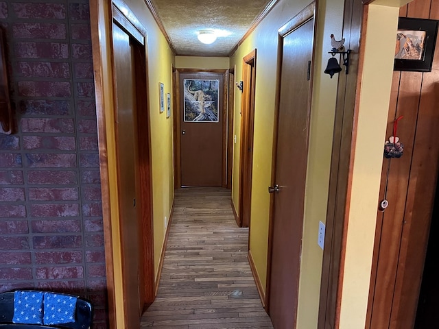 hall featuring hardwood / wood-style floors, a textured ceiling, and crown molding