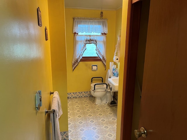 bathroom featuring tile patterned flooring, toilet, and crown molding