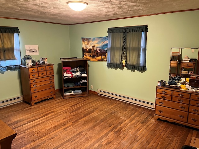 bedroom with a baseboard heating unit, a textured ceiling, and hardwood / wood-style flooring