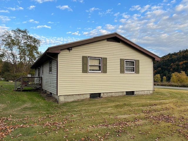 view of side of home featuring a lawn and a wooden deck