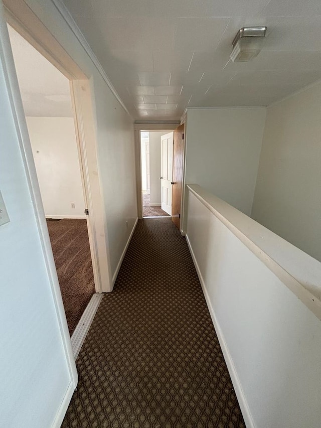 hallway featuring ornamental molding and dark carpet