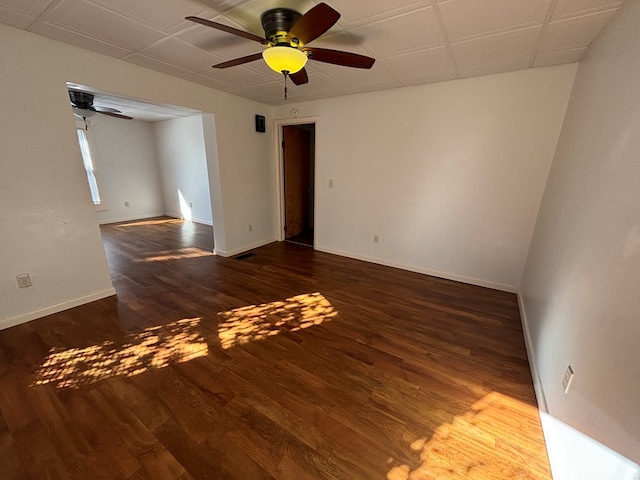 unfurnished room with a drop ceiling, dark hardwood / wood-style floors, and ceiling fan