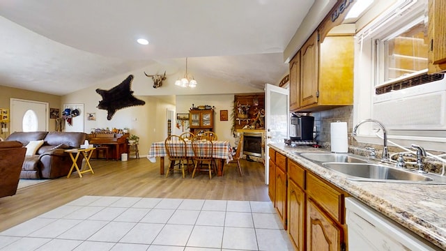 kitchen featuring sink, hanging light fixtures, white dishwasher, lofted ceiling, and decorative backsplash