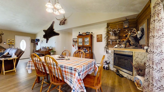 dining room featuring a textured ceiling, wood-type flooring, and vaulted ceiling