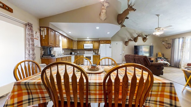 dining room featuring ceiling fan, sink, light hardwood / wood-style floors, and vaulted ceiling