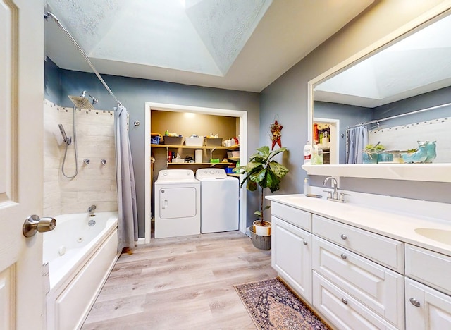 bathroom featuring vanity, washing machine and dryer, shower / bathtub combination with curtain, a textured ceiling, and wood-type flooring