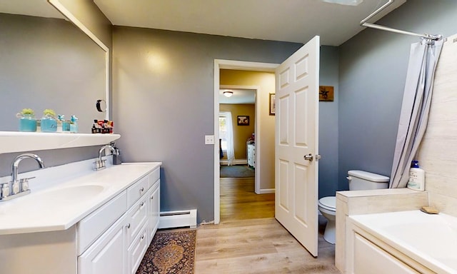 bathroom with a tub, baseboard heating, toilet, vanity, and hardwood / wood-style flooring