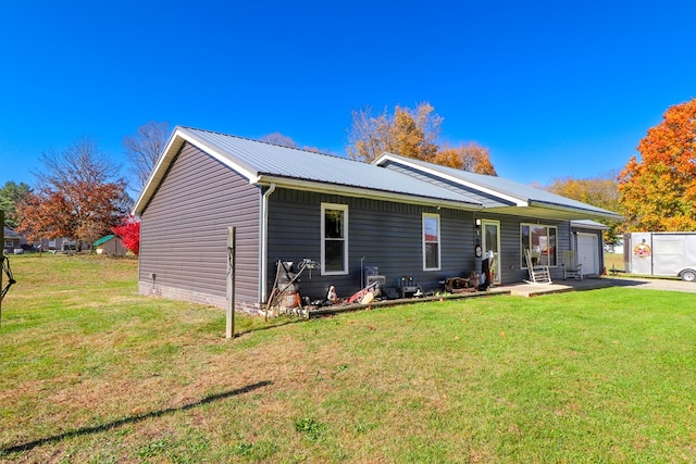 rear view of property with a garage and a yard