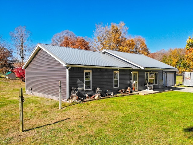 back of property with a garage and a lawn