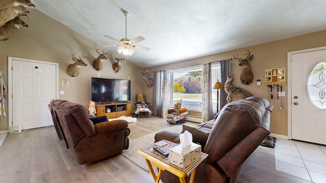 living room with hardwood / wood-style flooring, ceiling fan, a textured ceiling, and vaulted ceiling