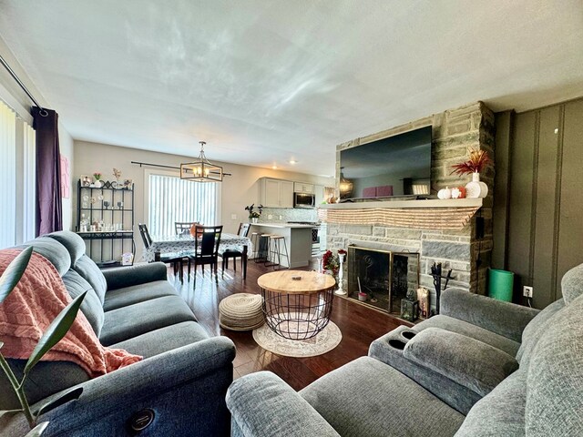 living room with a stone fireplace, hardwood / wood-style floors, and a notable chandelier