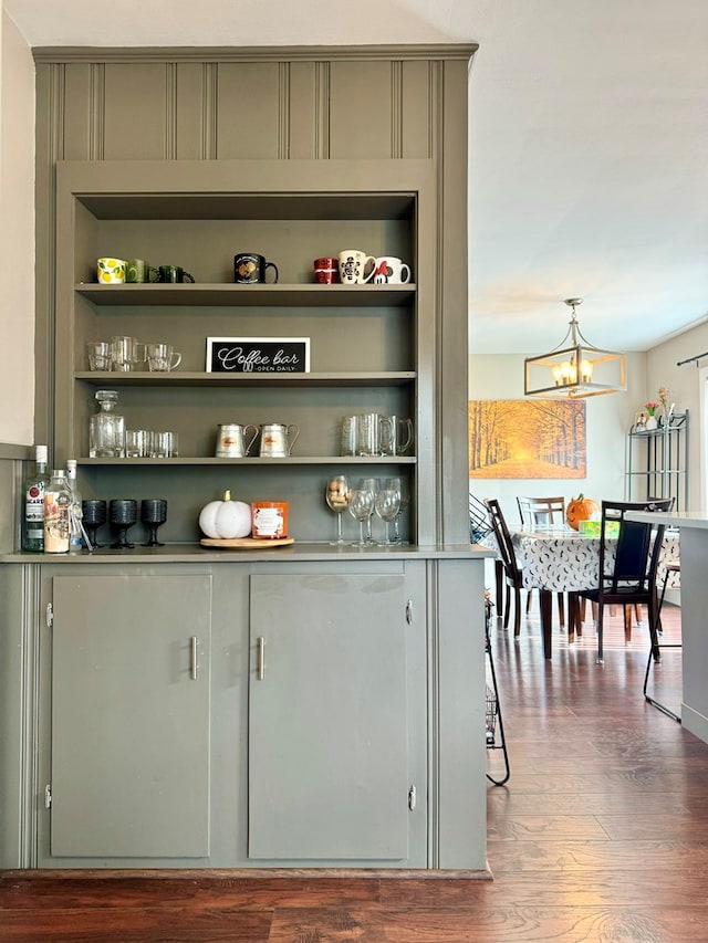 bar featuring wood-type flooring, gray cabinetry, hanging light fixtures, an inviting chandelier, and built in shelves