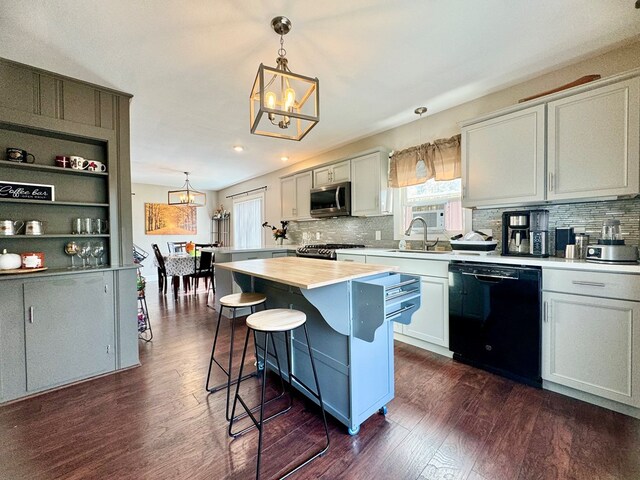 kitchen featuring a kitchen island, black dishwasher, hanging light fixtures, white cabinets, and dark wood-type flooring