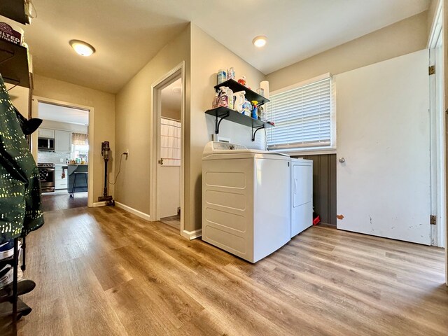 laundry area featuring washing machine and clothes dryer and light hardwood / wood-style floors