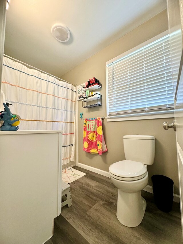 bathroom with a shower with curtain, wood-type flooring, and toilet