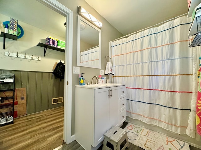 bathroom featuring shower / bath combo, vanity, wooden walls, and hardwood / wood-style flooring