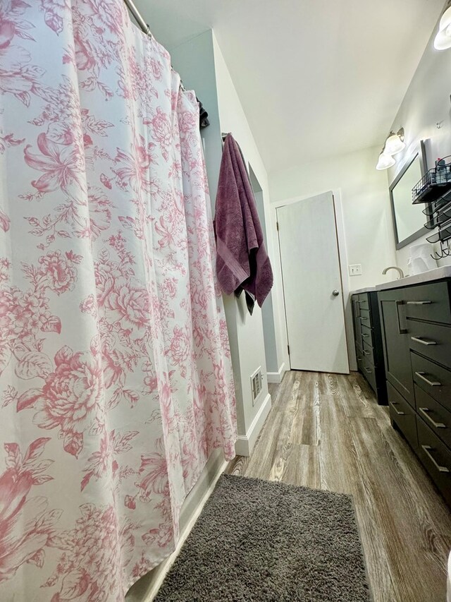 bathroom with walk in shower, wood-type flooring, and vanity