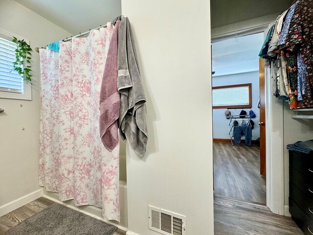 bathroom featuring a wealth of natural light, wood-type flooring, and shower / tub combo