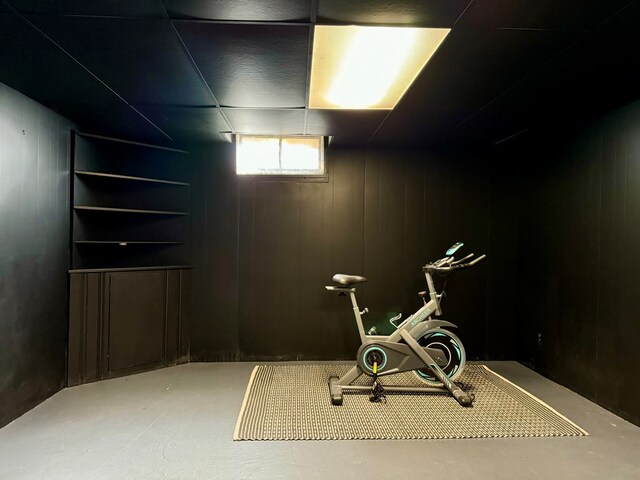 workout room featuring wood walls and concrete floors