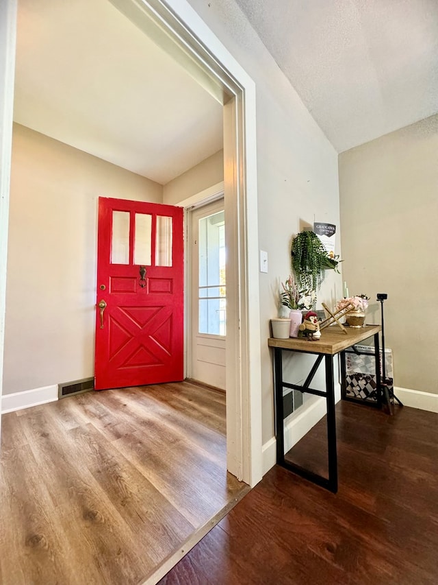 foyer with hardwood / wood-style floors and vaulted ceiling