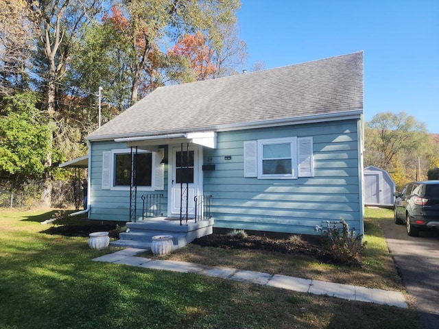 view of front of home featuring a front yard and a storage shed