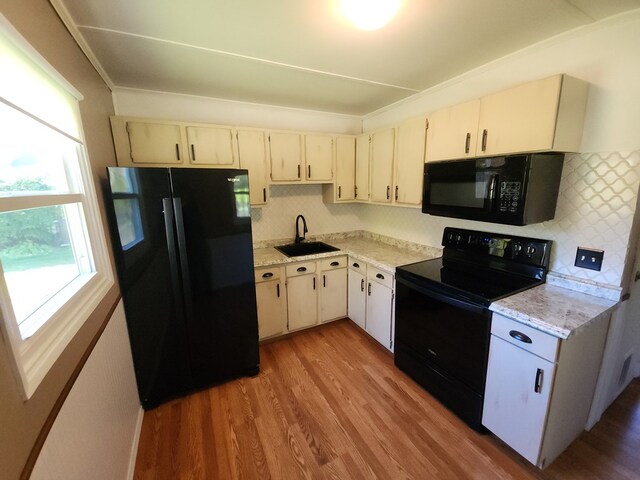 kitchen featuring backsplash, light hardwood / wood-style floors, sink, and black appliances